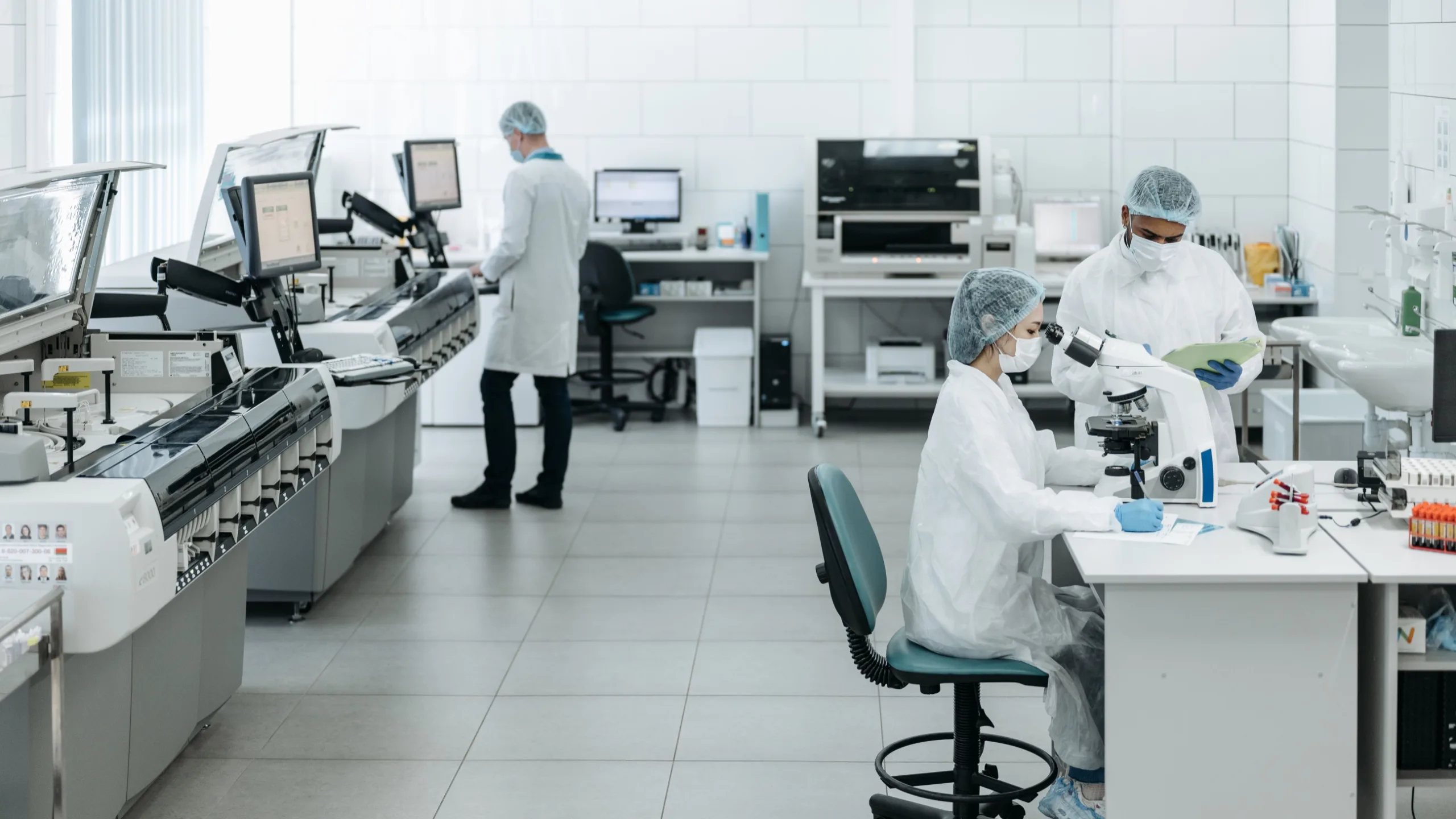 Equipe técnica operando analisadores e microscópio em laboratório de controle de qualidade