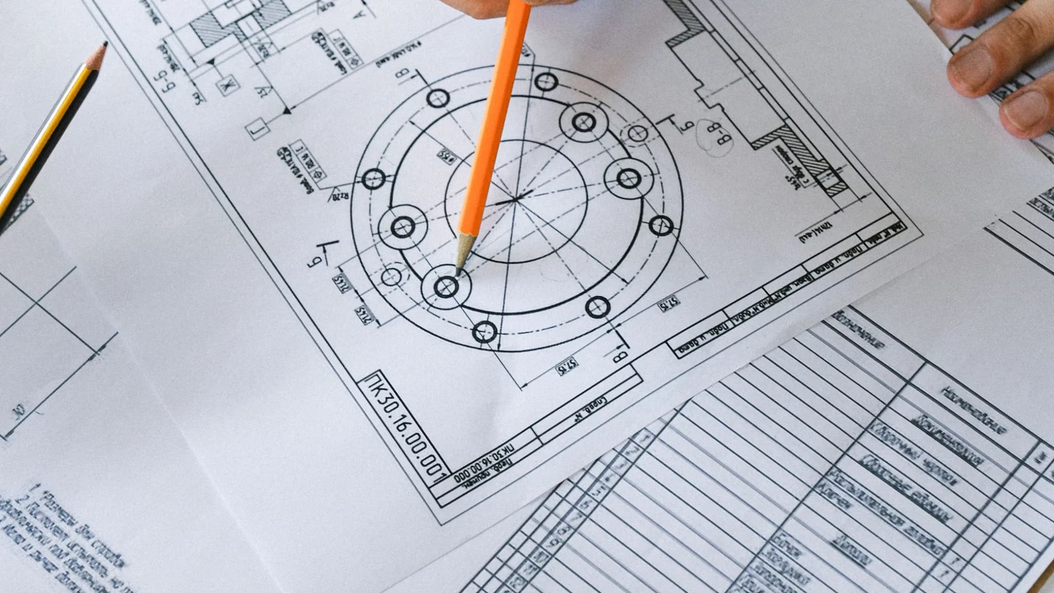 Engenheiro marcando cotas em desenho técnico a lápis sobre a mesa